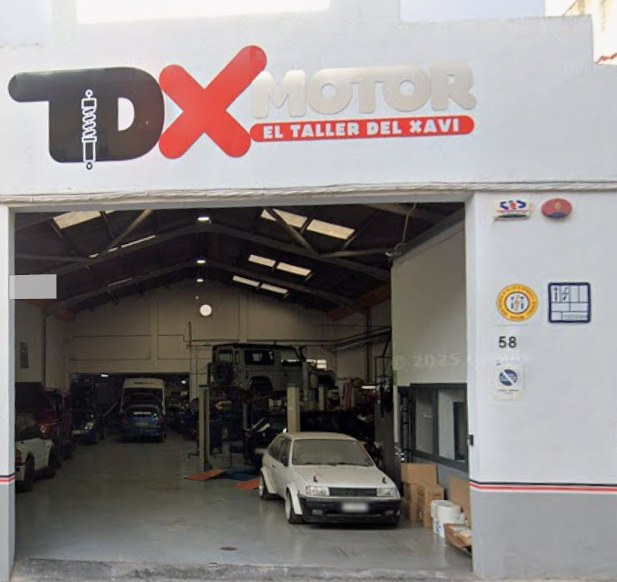 Fachada de TDX Motor en el Carrer del Progrés, 58: nave blanca con el rótulo TDX Motor, El Taller del Xavi, y el taller abierto con coches dentro